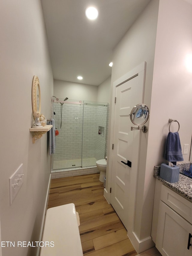 full bath featuring baseboards, toilet, wood finished floors, a shower stall, and recessed lighting