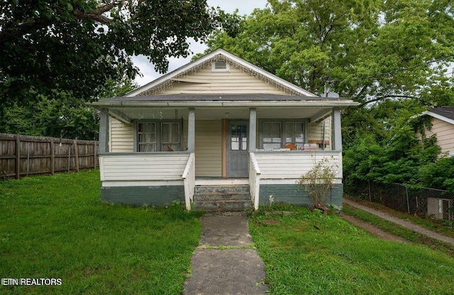 bungalow-style house featuring covered porch and a front yard