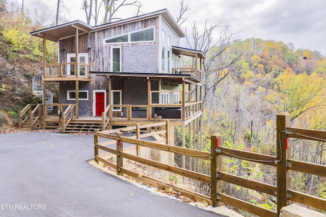 chalet / cabin featuring a wooden deck, a balcony, and fence