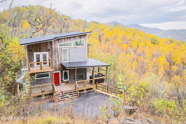 view of front of home with a deck with mountain view and a view of trees