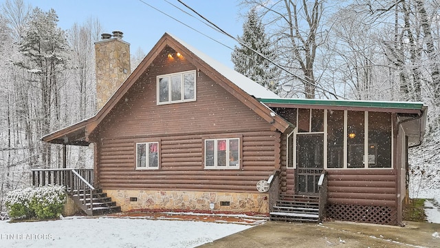 snow covered property featuring crawl space, a sunroom, a chimney, and log exterior