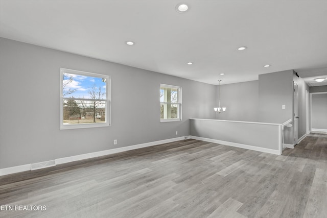 unfurnished room with wood-type flooring and an inviting chandelier