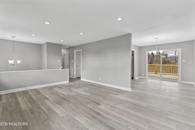 spare room featuring an inviting chandelier and light hardwood / wood-style flooring