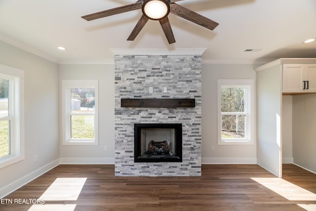 unfurnished living room with ceiling fan, ornamental molding, dark wood-type flooring, and a stone fireplace