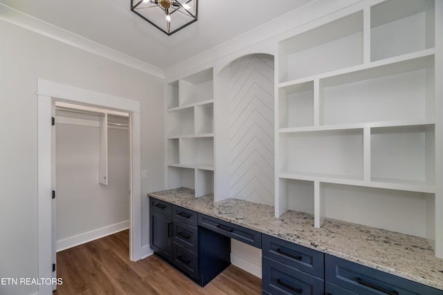 unfurnished office featuring hardwood / wood-style flooring, built in desk, and built in shelves