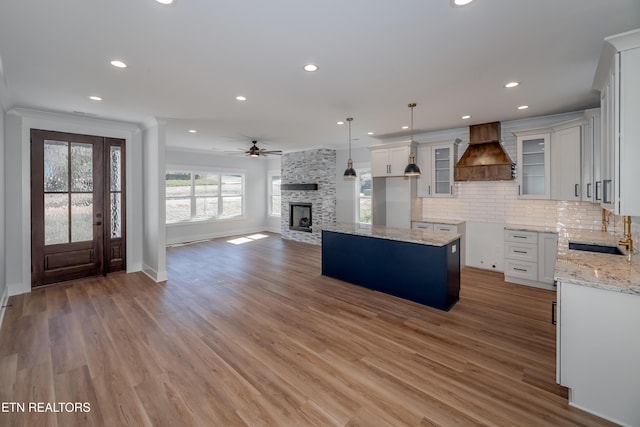 kitchen with sink, premium range hood, a center island, decorative light fixtures, and white cabinets