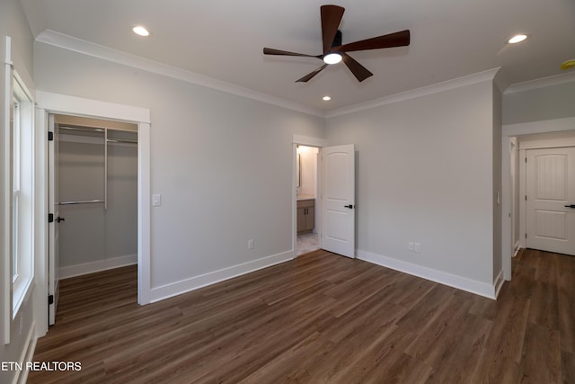 unfurnished bedroom with dark hardwood / wood-style flooring, ornamental molding, a walk in closet, and a closet