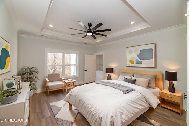 bedroom with a tray ceiling, hardwood / wood-style floors, and crown molding