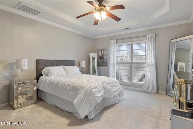 bedroom featuring visible vents, ornamental molding, a tray ceiling, and light colored carpet