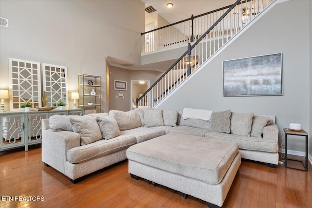 living room featuring stairway, visible vents, and wood finished floors