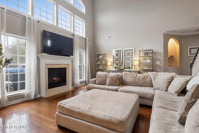 living room featuring visible vents, dark wood-type flooring, a fireplace with flush hearth, and a healthy amount of sunlight