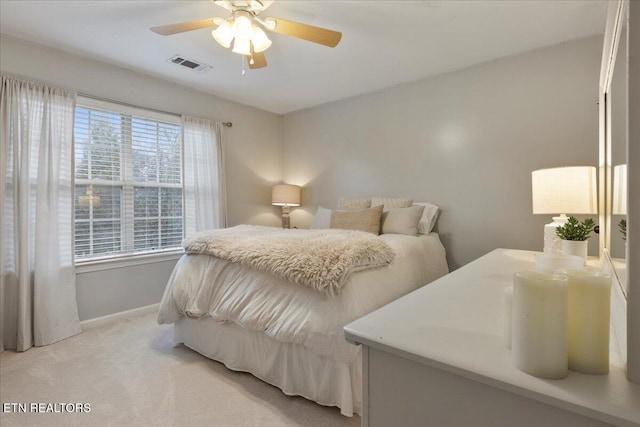 bedroom with baseboards, a ceiling fan, visible vents, and light colored carpet