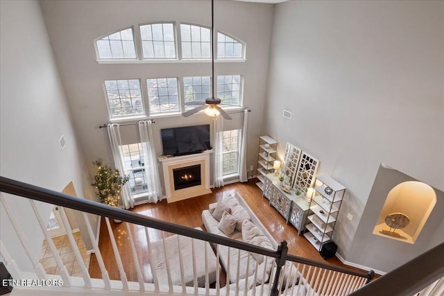 living area featuring stairs, wood finished floors, a fireplace with flush hearth, and a towering ceiling