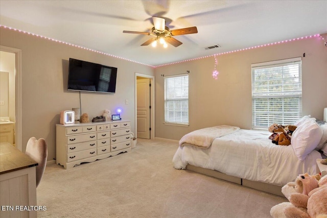 bedroom with light carpet, ceiling fan, visible vents, and ensuite bathroom