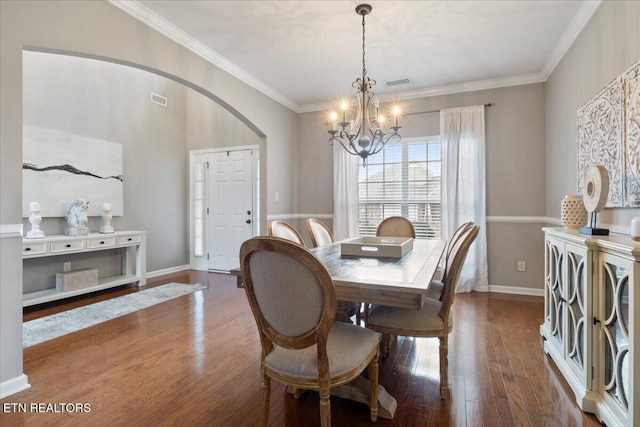 dining space with a notable chandelier, crown molding, visible vents, and wood finished floors