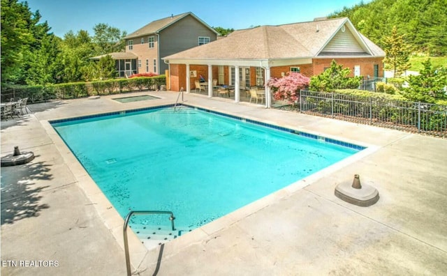 community pool with a patio and fence