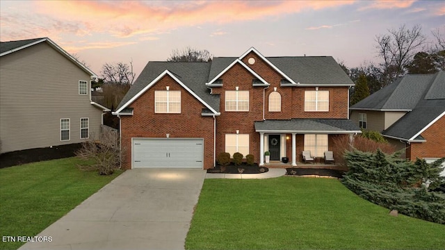 view of front of house with a garage, brick siding, concrete driveway, and a yard