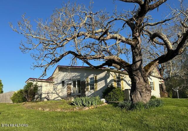 view of side of home featuring fence and a yard