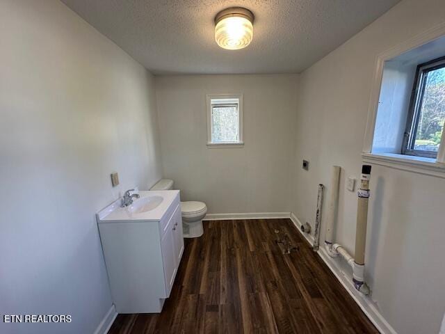 half bathroom with wood finished floors, baseboards, a textured ceiling, and toilet