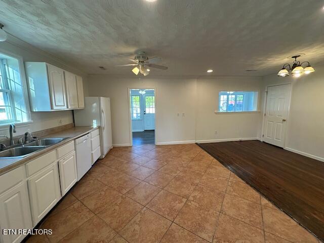 kitchen featuring white cabinets, a healthy amount of sunlight, white appliances, and ceiling fan with notable chandelier