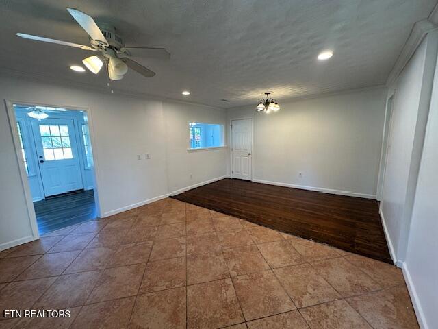 empty room with ceiling fan with notable chandelier, tile patterned floors, baseboards, and recessed lighting