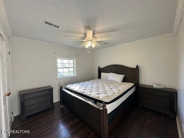 bedroom with wood finished floors, visible vents, ornamental molding, and a ceiling fan