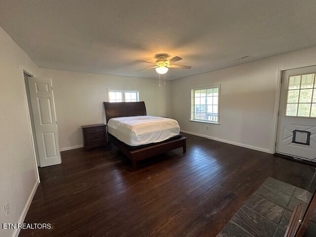 bedroom with baseboards, a ceiling fan, and dark wood-type flooring