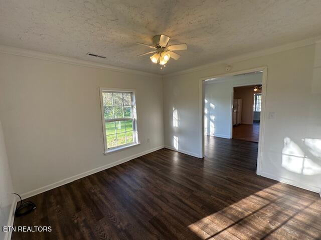 unfurnished room with ceiling fan, visible vents, crown molding, baseboards, and dark wood-style flooring