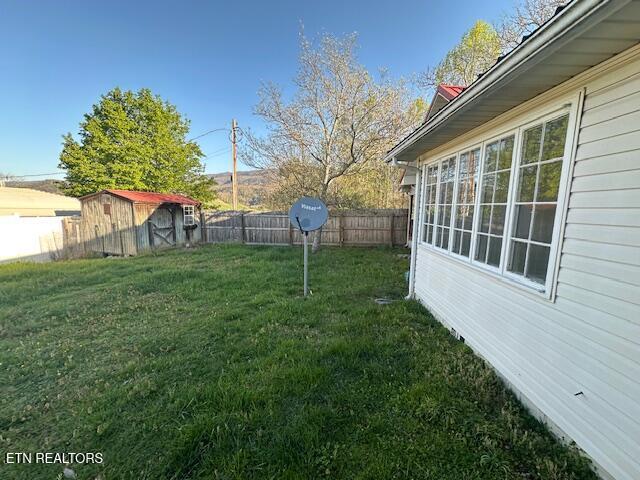 view of yard with a fenced backyard, an outbuilding, and a storage shed