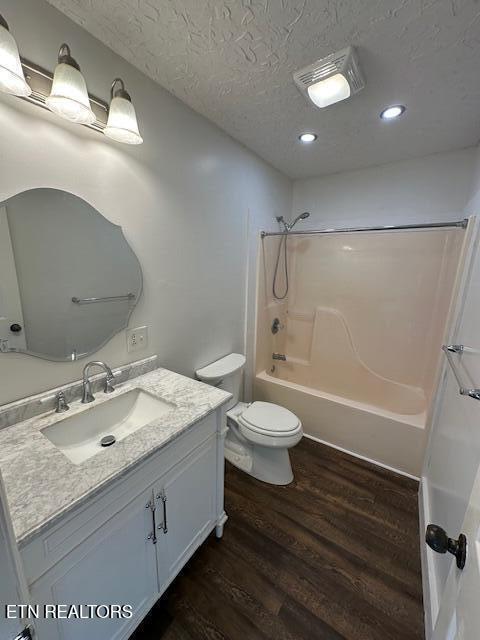 bathroom featuring wood finished floors, vanity, washtub / shower combination, toilet, and recessed lighting