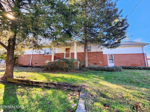 view of side of home with crawl space, brick siding, and a yard