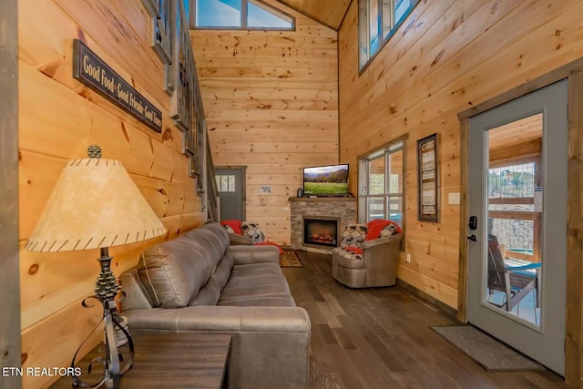 living room featuring wooden walls, dark hardwood / wood-style flooring, a high ceiling, and a fireplace