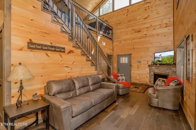 living room featuring a fireplace, a towering ceiling, wood walls, and wood-type flooring