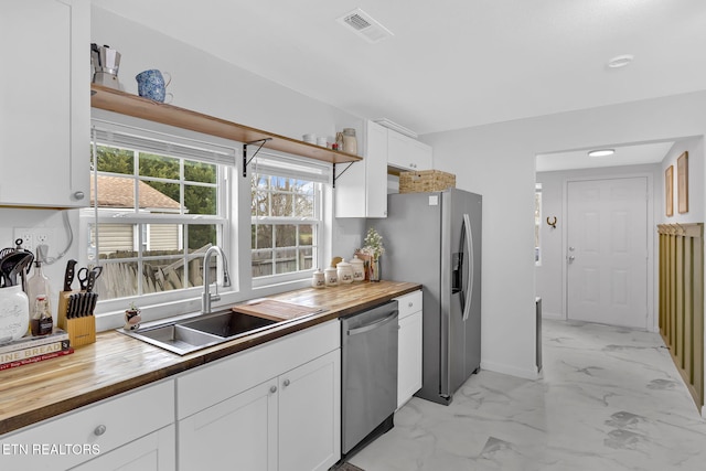 kitchen with sink, white cabinets, stainless steel appliances, and wooden counters