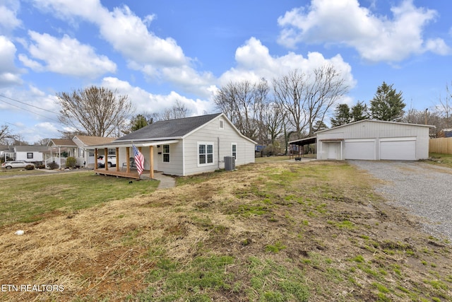 view of side of property featuring central AC unit, a lawn, covered porch, a garage, and an outdoor structure