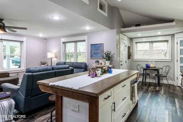 kitchen with dark wood-style flooring, recessed lighting, open floor plan, white cabinets, and a kitchen island