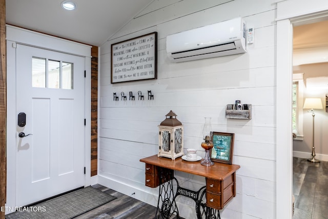 entrance foyer featuring wood finished floors, vaulted ceiling, baseboards, and a wall mounted AC