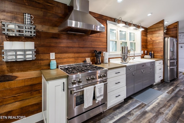 kitchen with white cabinetry, wall chimney exhaust hood, appliances with stainless steel finishes, and a sink