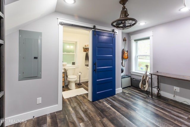 bedroom with dark wood-style flooring, electric panel, baseboards, and a barn door