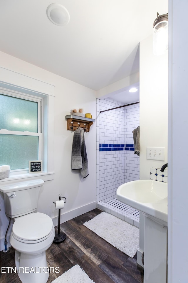 bathroom featuring baseboards, a shower stall, toilet, and wood finished floors