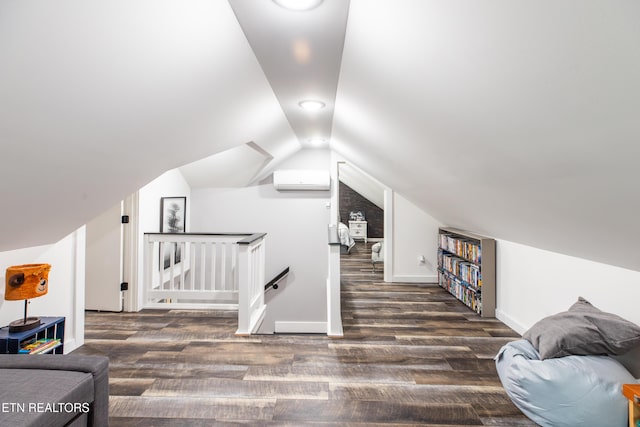 additional living space featuring a wall unit AC, baseboards, vaulted ceiling, and dark wood-style flooring