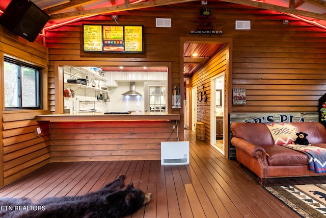 interior space featuring lofted ceiling, visible vents, wood walls, and wood finished floors