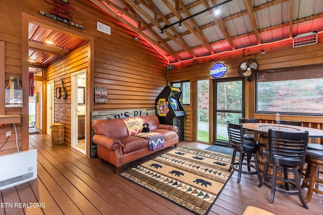 living area featuring lofted ceiling, wood walls, visible vents, and wood finished floors