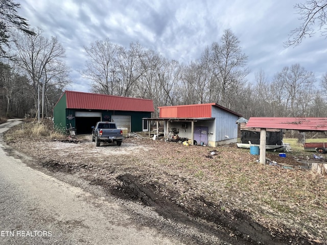 view of front of house featuring metal roof, driveway, and an outdoor structure