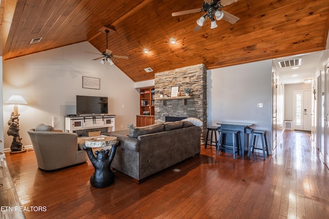 living area with wood ceiling, wood-type flooring, visible vents, and a stone fireplace