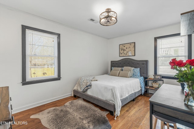 bedroom featuring light wood-type flooring, visible vents, and baseboards