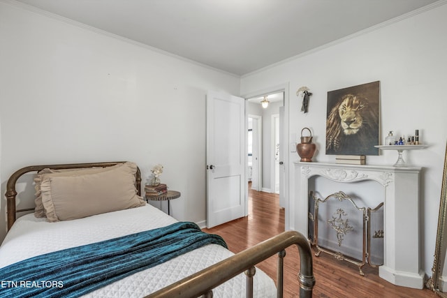bedroom with ornamental molding, baseboards, and wood finished floors