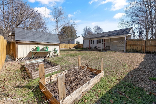 view of yard featuring a storage shed, an outdoor structure, a fenced backyard, and a garden