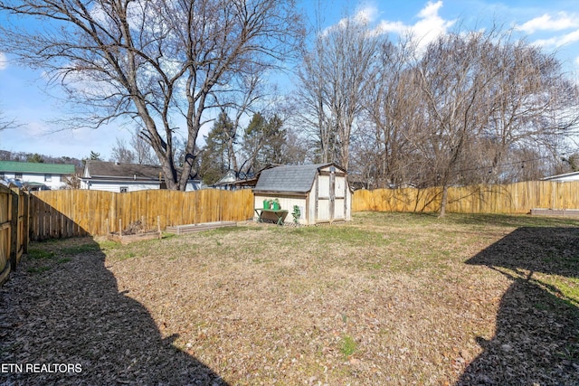 view of yard featuring a shed, a fenced backyard, and an outbuilding