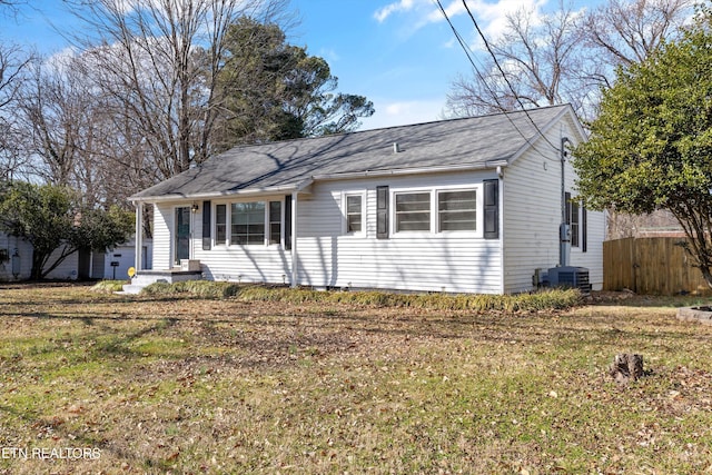 view of front of house featuring a shingled roof, a front yard, central AC, and fence